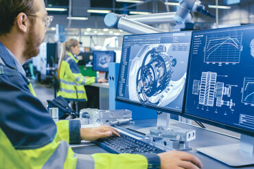 Mechanical Engineer Works on Computer with factory in background